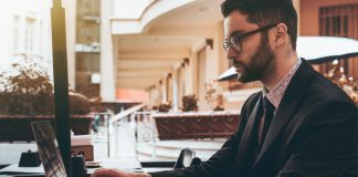 Man employer in glasses with laptop in street restaurant